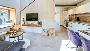 A modern living room with a sofa, a coffee table, and a TV mounted on a wooden wall.