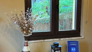 Habitación con ventana que da a un jardín, un jarrón decorativo, un farol y una placa que indica un premio de viaje.