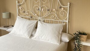 Una cama bien hecha con sábanas blancas y un cabecero de metal decorativo.