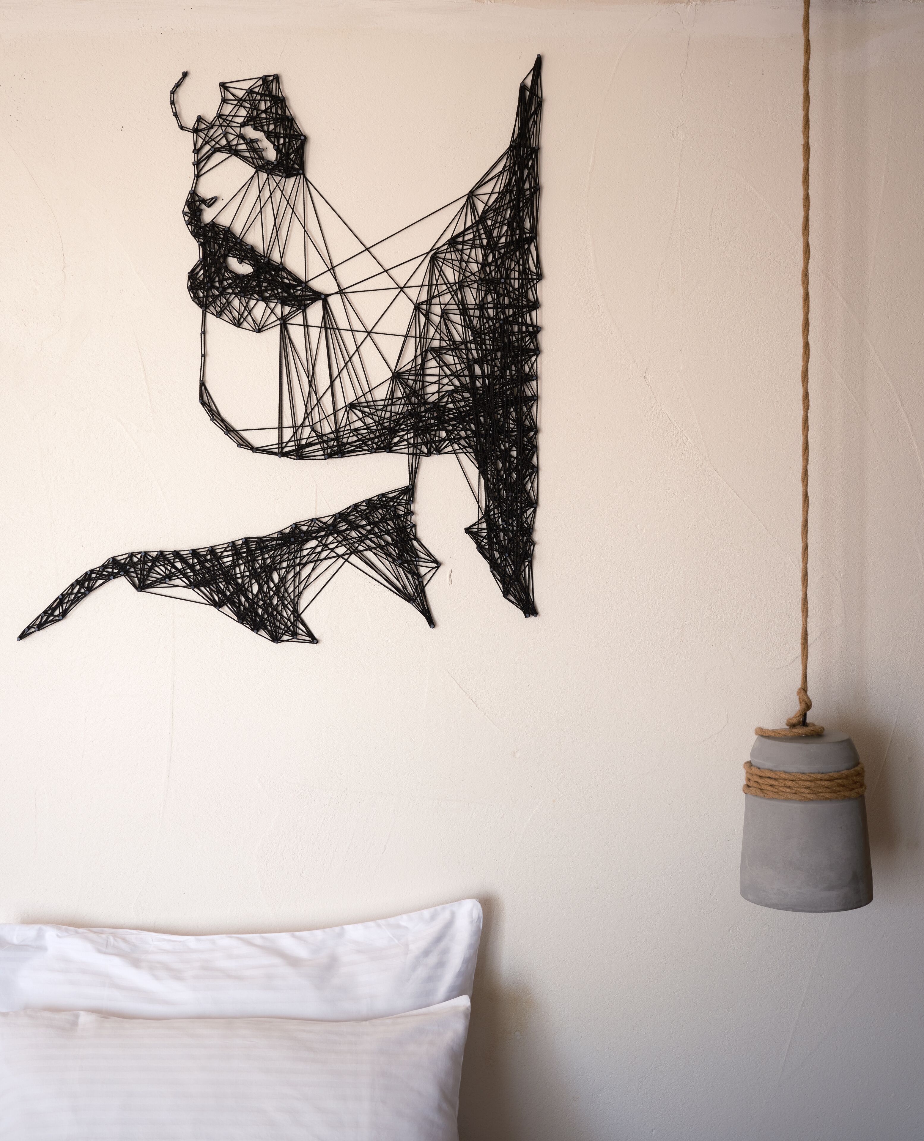A wall with a geometric black wire art piece and a hanging light fixture.