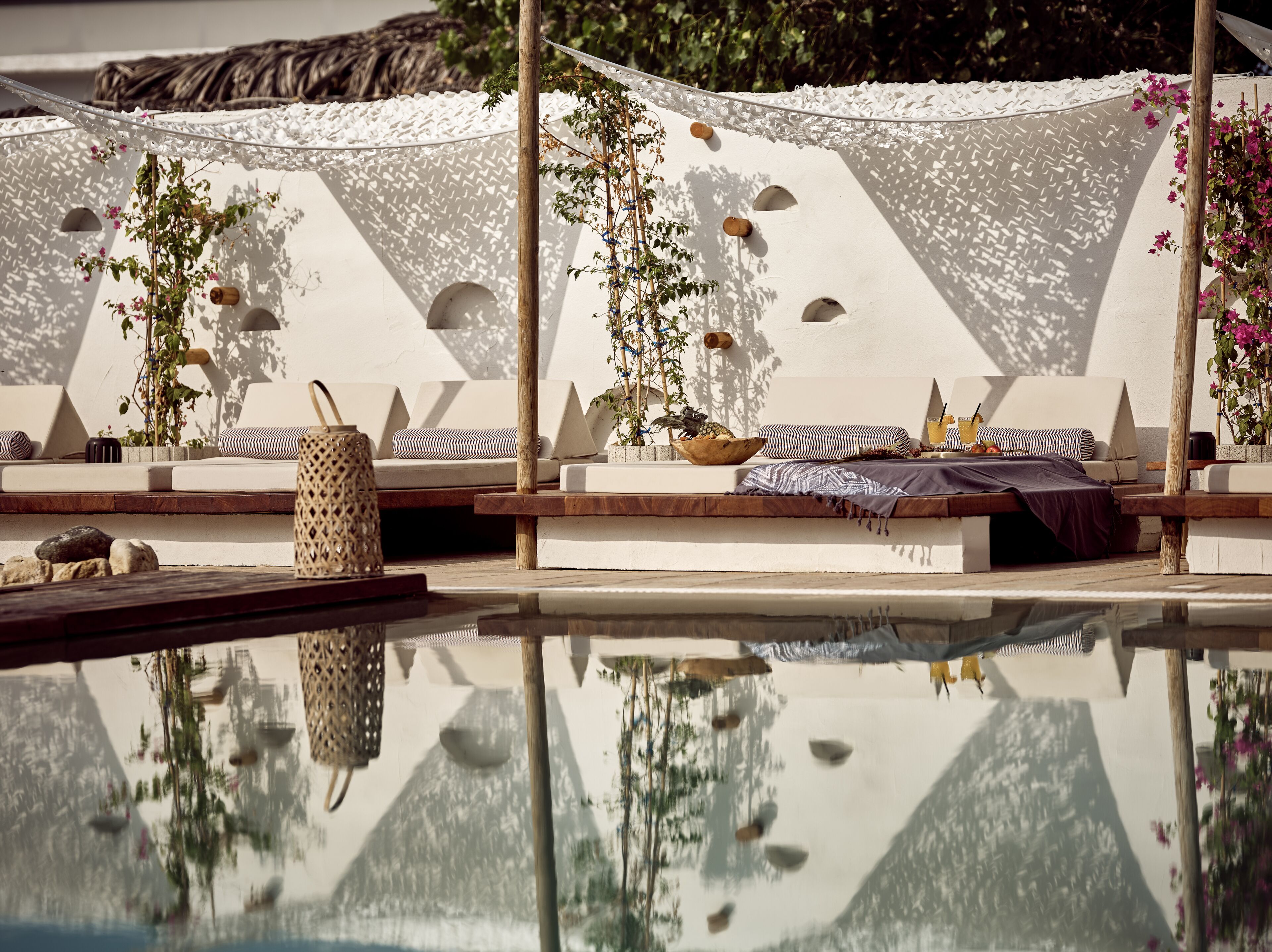 A poolside area with lounge chairs, a wooden table, and a decorative umbrella.