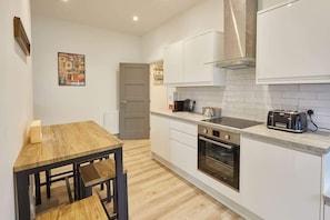Une cuisine moderne avec des meubles blancs, une table en bois et un four encastré.