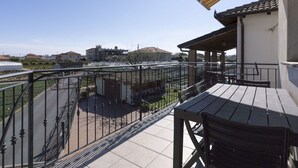 Un balcón con vista a un jardín y edificios a lo lejos.