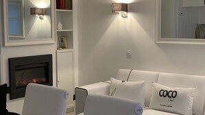 Una sala de estar moderna con chimenea, sofás blancos y una estantería.