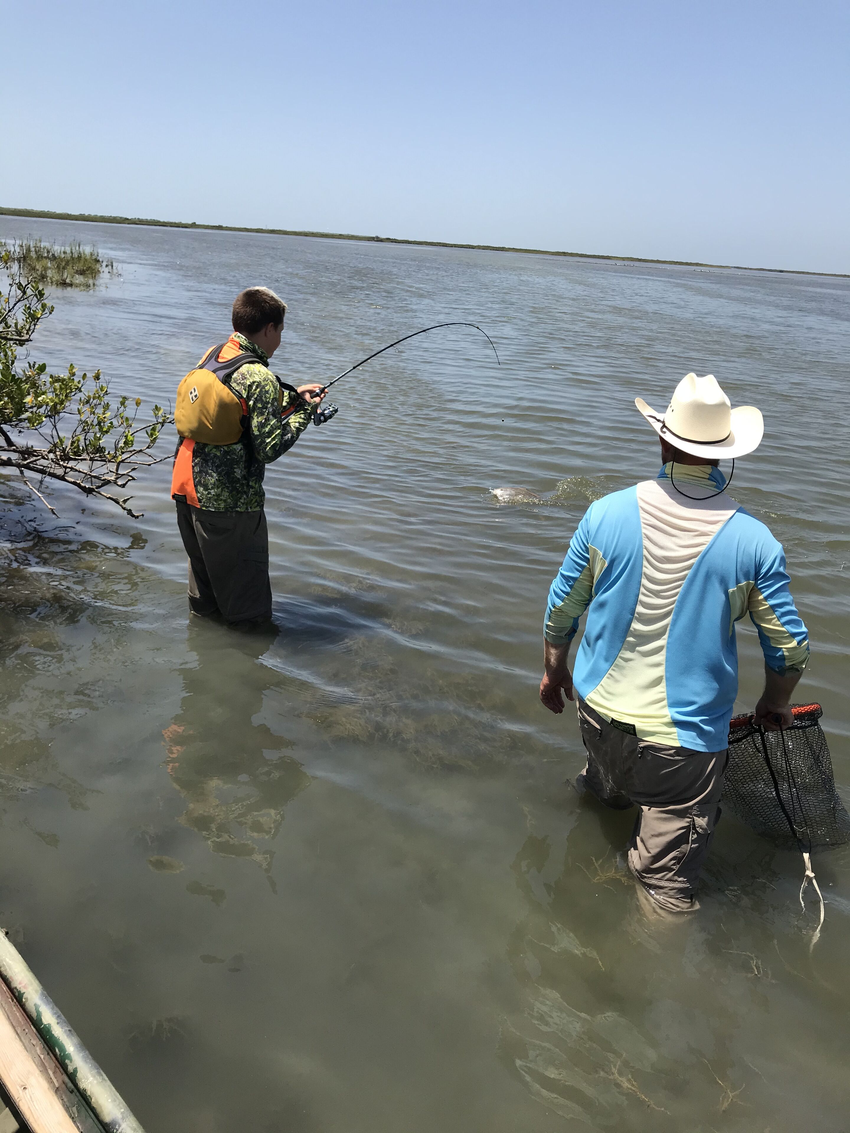 Deux personnes sont en train de pêcher dans un plan d’eau calme.