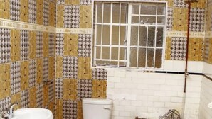 A bathroom with patterned tiles, a sink, toilet, and bathtub. - Rest Guest House (Harare)