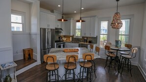 Una cocina moderna con armarios blancos, electrodomésticos de acero inoxidable y una isla central con taburetes de bar.
