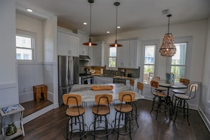 Una cocina moderna con armarios blancos, electrodomésticos de acero inoxidable y una isla central con taburetes de bar.