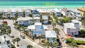 A coastal residential area with houses, a beach, and a walkway leading to beach chairs.
