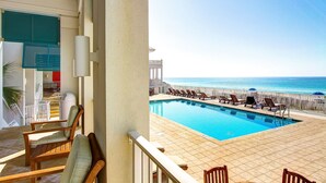 A poolside area with lounge chairs and a view of the ocean.