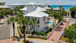A coastal residential area with white houses, palm trees, and a clear view of the ocean.