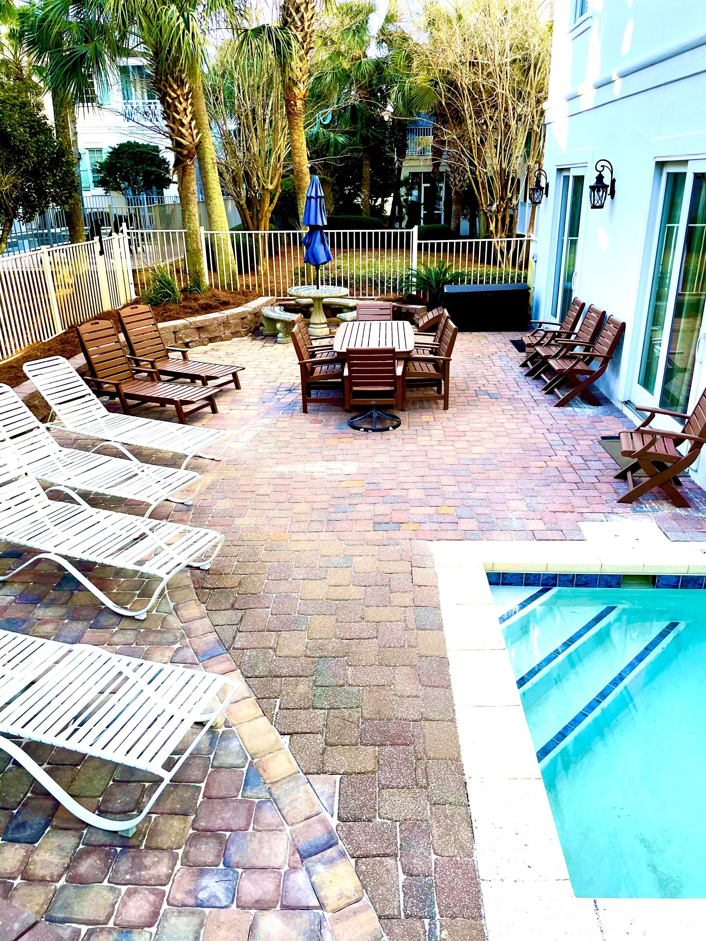 Ein Außenbereich mit Terrasse, Pool, Liegestühlen und einem Esstisch.