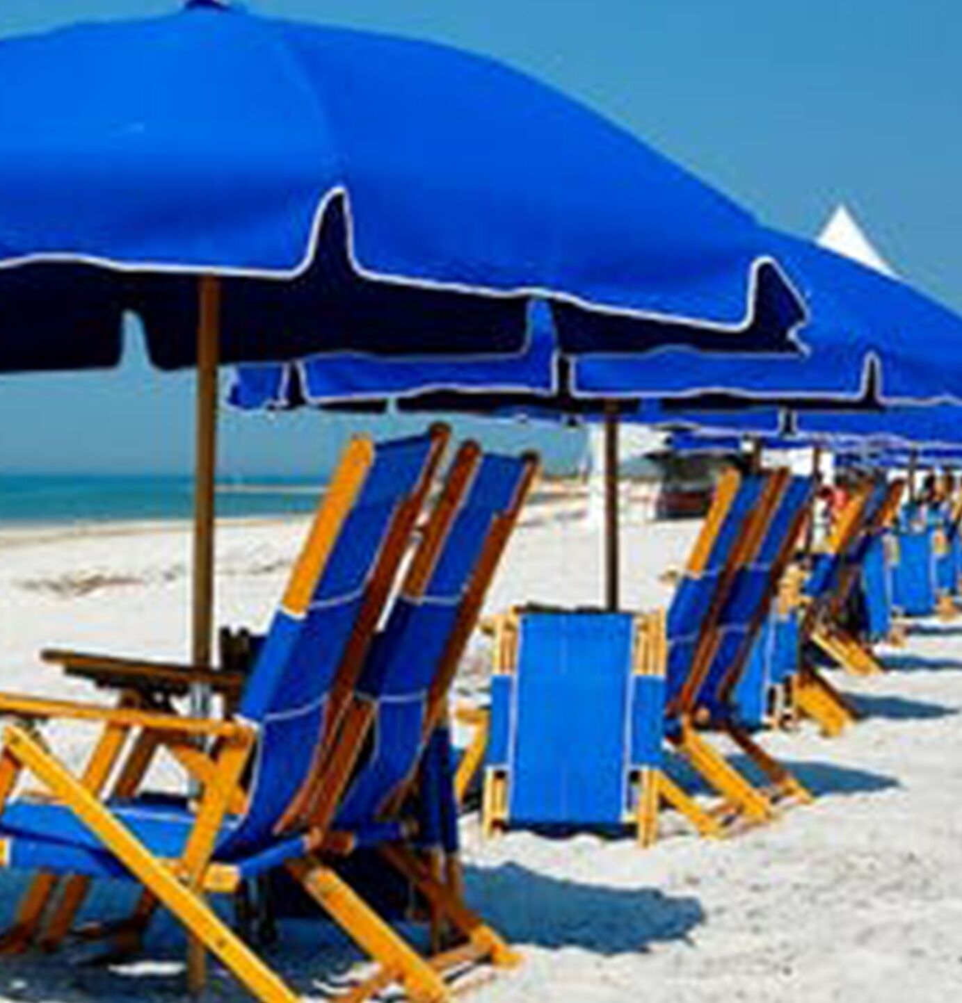 Een rij strandstoelen en parasols op een zandstrand.