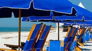Eine Reihe von Liegestühlen und Sonnenschirmen an einem Sandstrand.