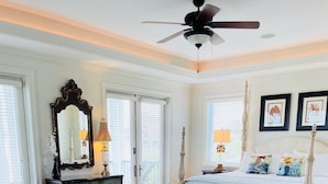 Ein Schlafzimmer mit einem Bett, einem Schminktisch, einem Spiegel, einem Deckenventilator und einem großen Teppich mit Blumenmuster.