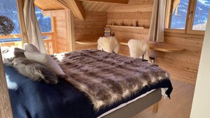 Un dormitorio de cabaña de madera con cama, manta de piel y vistas a las montañas.