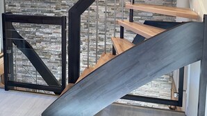 Un interior moderno con una escalera de caracol, pared de piedra y vigas de madera.