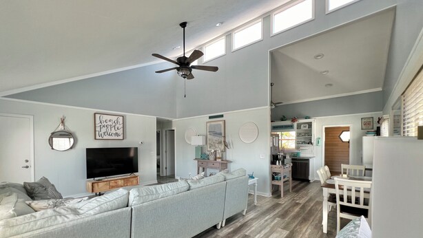 A spacious living area with a sectional sofa, a television, and a ceiling fan. - Beach Goals! 4 bedroom 2.5 bath home, just a 5 minute walk to beach!!! (Sunset Beach)