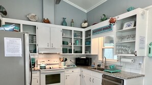 A kitchen with white cabinets, a stove, a microwave, and a sink. There is a sign above the sink that reads "SEAFOOD SHACK". - Beach Goals! 4 bedroom 2.5 bath home, just a 5 minute walk to beach!!! (Sunset Beach)
