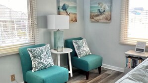 A modern living room with teal armchairs, a white side table, and artwork on the walls. - Beach Goals! 4 bedroom 2.5 bath home, just a 5 minute walk to beach!!! (Sunset Beach)