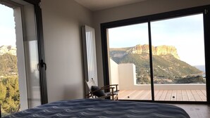 Une chambre dotée d’un grand lit, d’une chaise et offrant une vue sur un paysage montagneux grâce à une porte-fenêtre coulissante.