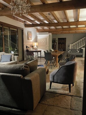 A spacious living area with a dining table, sofas, and a staircase leading to another level.