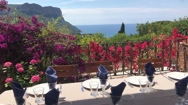 Une table dressée pour le dîner, avec vue sur la mer et les montagnes.