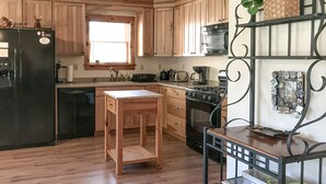 Cucina con mobili in legno, frigorifero nero, fornello e una finestra.