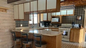 Une cuisine dotée d’un grand îlot central, de meubles en bois, d’un four à micro-ondes, d’une cuisinière et de tabourets de bar.