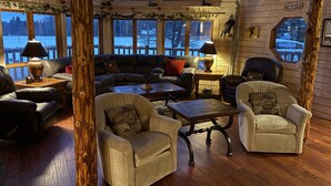L’intérieur chaleureux d’un chalet avec des murs en bois, de grandes fenêtres et une cheminée.