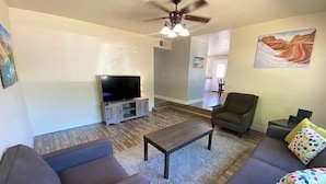 A living room with a flat-screen TV, a ceiling fan, a sofa, and a coffee table. - Family Home in Kanab w/ private Hot Tub, Near Zion (Kanab)