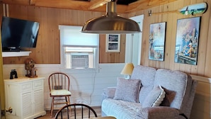 A cozy room with a wooden ceiling, a sofa, a table, and a television.