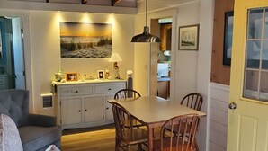 A cozy living room with a sofa, a dining table with chairs, and a kitchen area with a sink and cabinets.