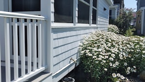 A white house with a porch and a garden with white flowers.