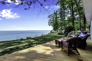 A wooden deck with wicker furniture overlooking a body of water.