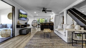 Uma sala de estar moderna com um sofá, mesa de centro e TV fixada na parede.