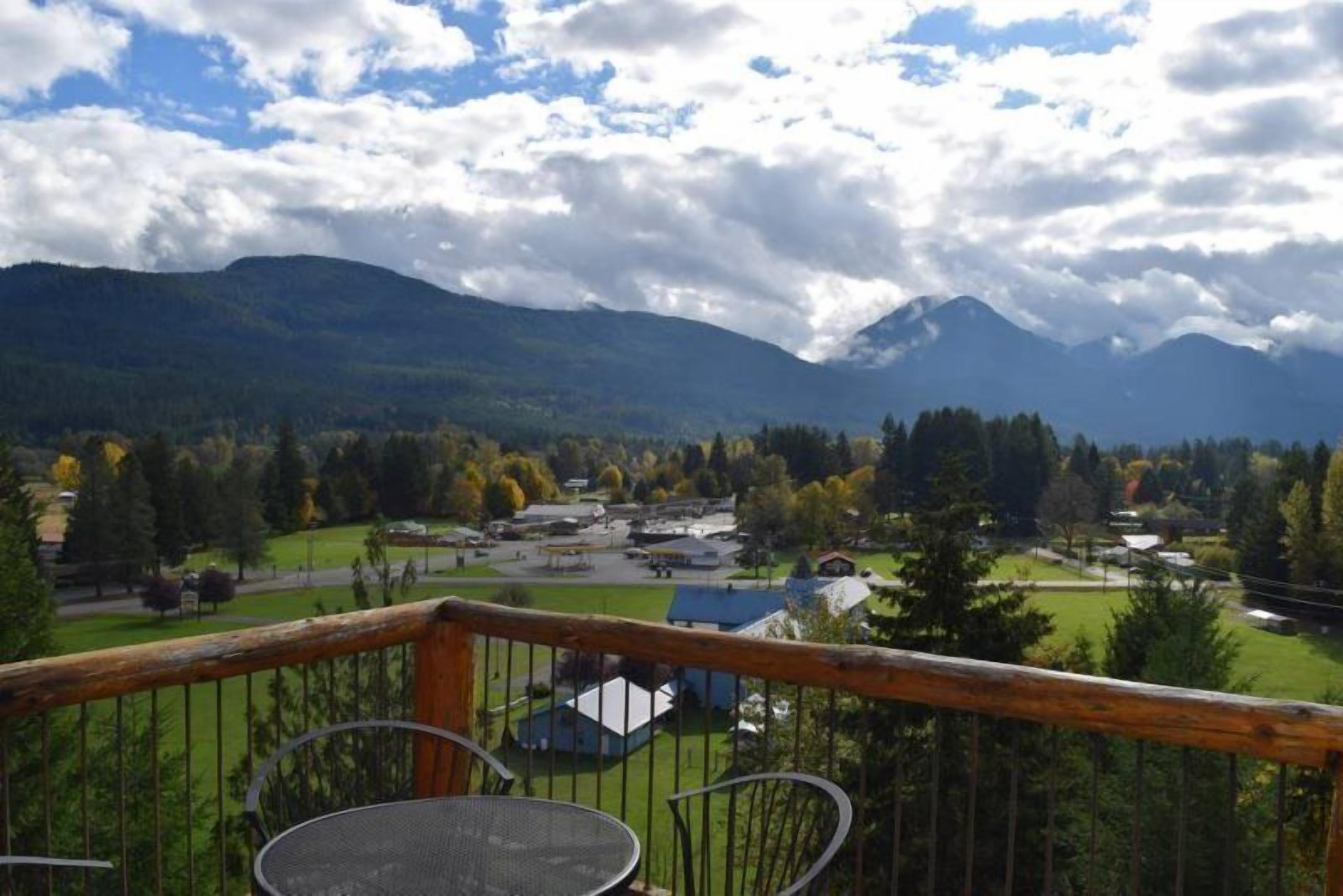 Ein Balkon mit Blick auf eine Berglandschaft, einem kleinen Tisch und Stühlen.