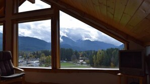 A room with a large window offering a view of mountains and a town. - Elk Ridge (Packwood)