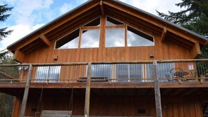A wooden cabin with a balcony, large windows, and a swing chair. - Elk Ridge (Packwood)