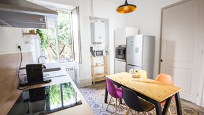 A modern kitchen with a wooden table, chairs, and a refrigerator.