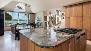 Una cocina amplia con una isla grande, armarios de madera y vistas al exterior.