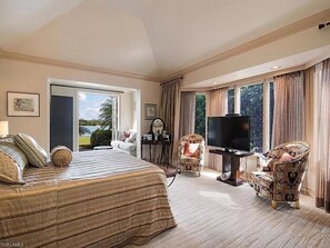 Relax in comfort with a large bed, TV, and armchairs in this cozy retreat.