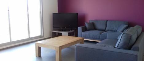 A living room with a sofa, a coffee table, and a TV.