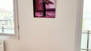 A room with a white bench, a window, and a wall-mounted painting.