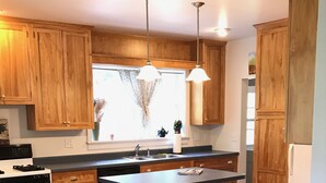 Une cuisine avec des meubles de rangement en bois, un îlot central, une cuisinière et un évier.