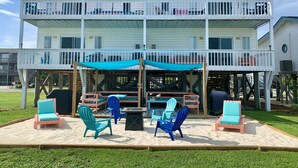 A two-story building with a balcony, outdoor seating area with chairs and a table, and a covered patio.