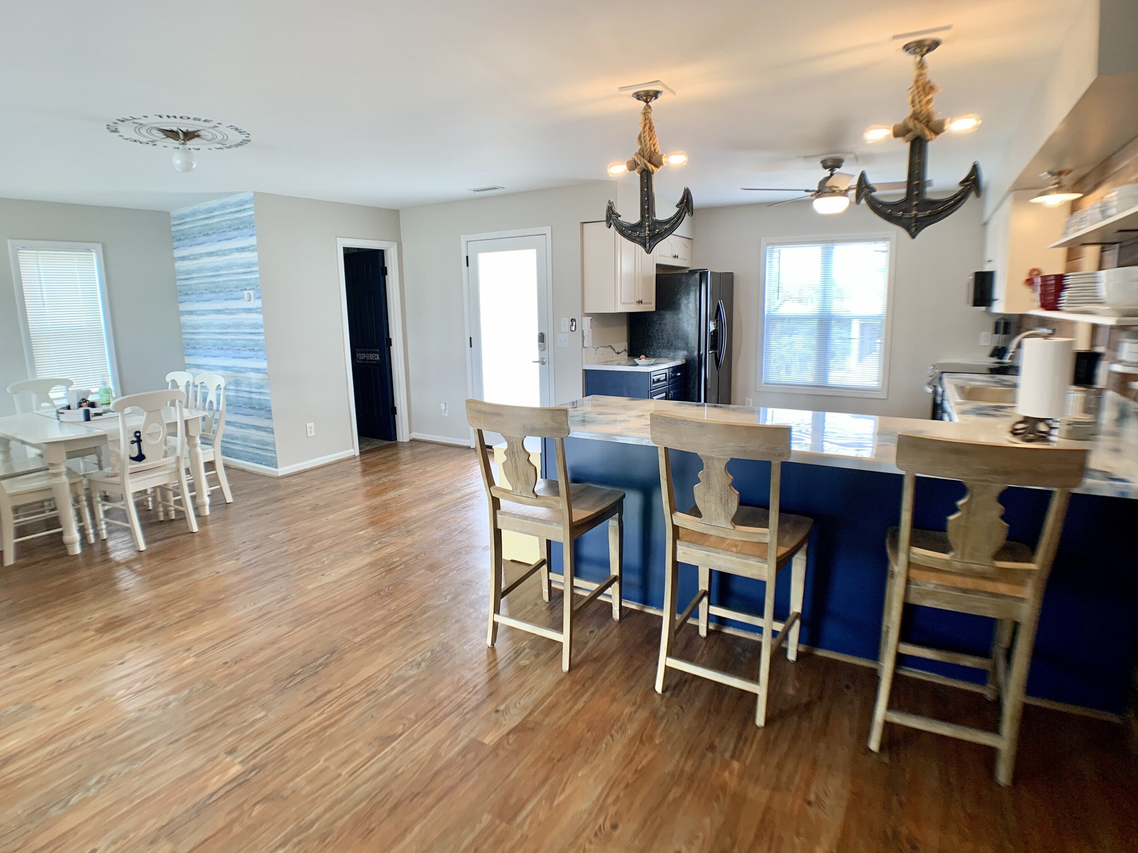 A spacious kitchen with a central island, wooden chairs, and a dining area with a white table and chairs.