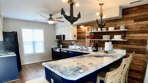 A modern kitchen with a central island, wooden accents, and bar seating.