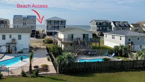 A residential area with beach access, featuring houses with balconies, a swimming pool, and a view of the ocean.
