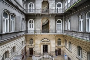 Un edificio de varios pisos con un patio central, que presenta ventanas de arco y balcones con barandillas de hierro forjado.